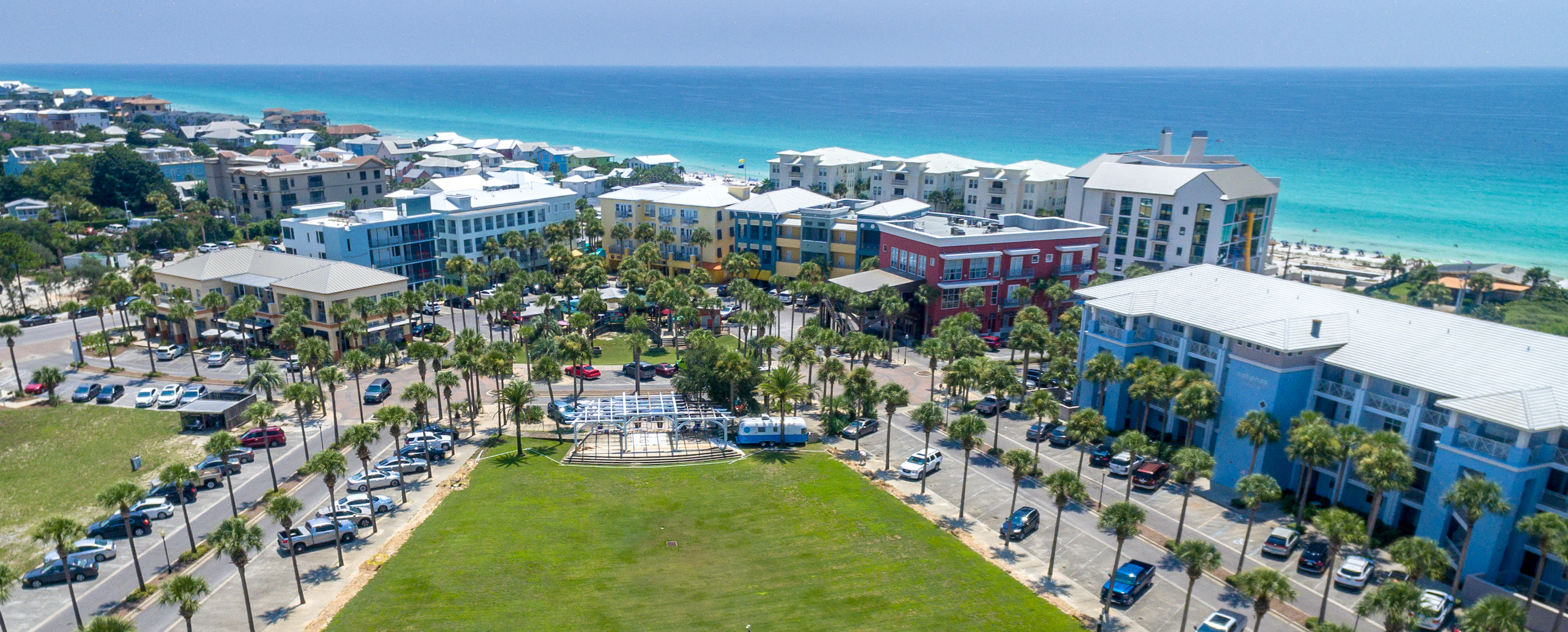 An aerial view of the Gulf Place town center including the lawn and blue gulf waters in the background